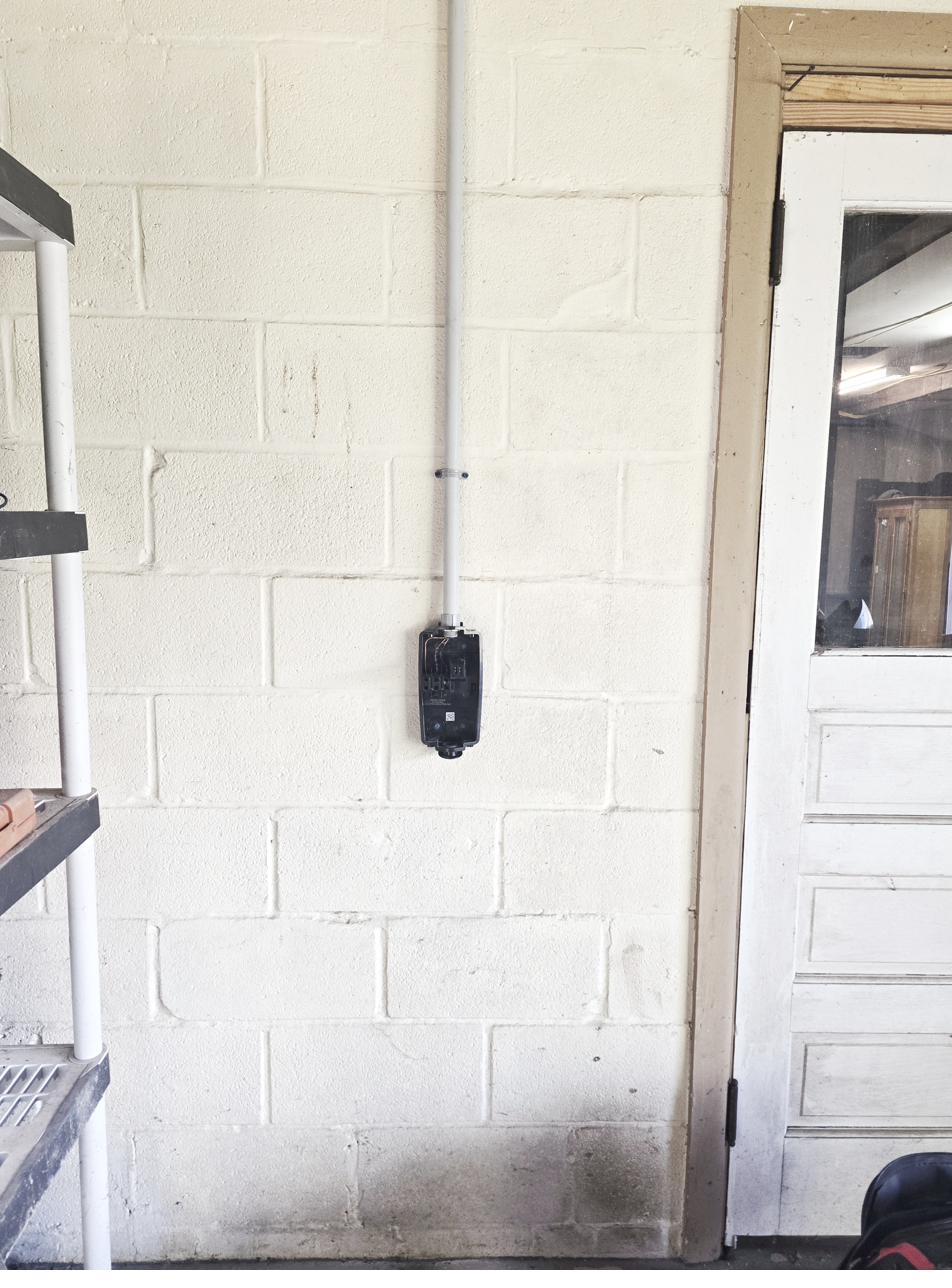 Conduit run on block wall during Tesla Universal Wall Connector install in Bellefonte