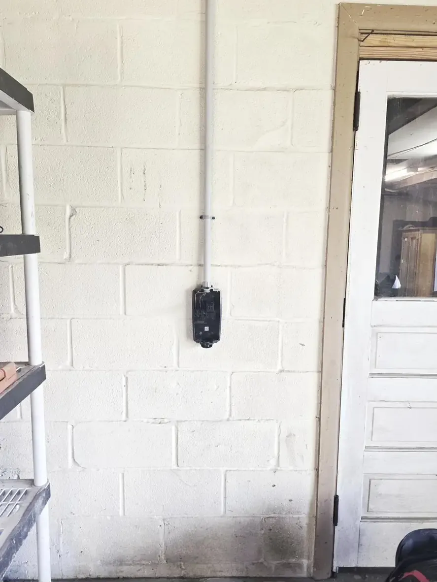 Conduit run on block wall during Tesla Universal Wall Connector install in Bellefonte