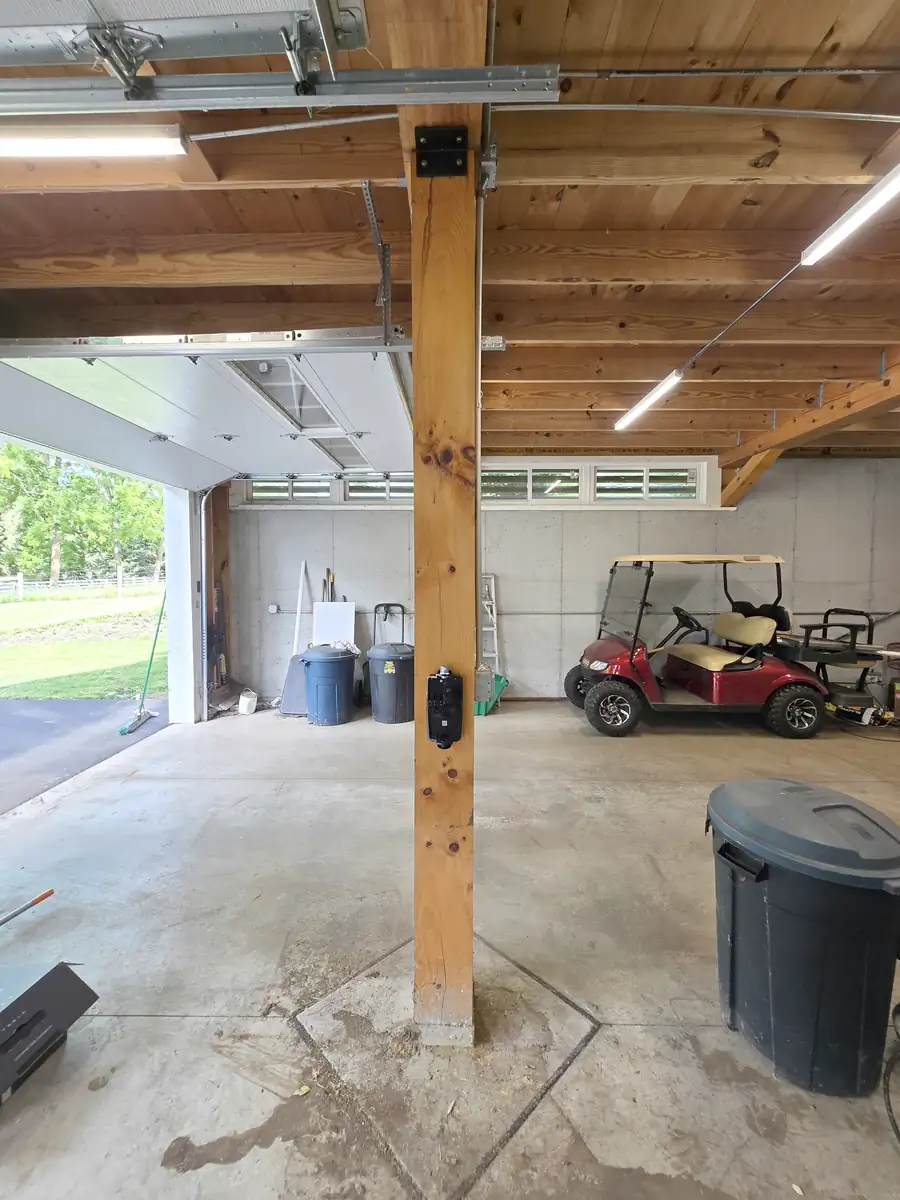 Weatherproof box mounted to the exposed garage beam during the Tesla Wall Connector install