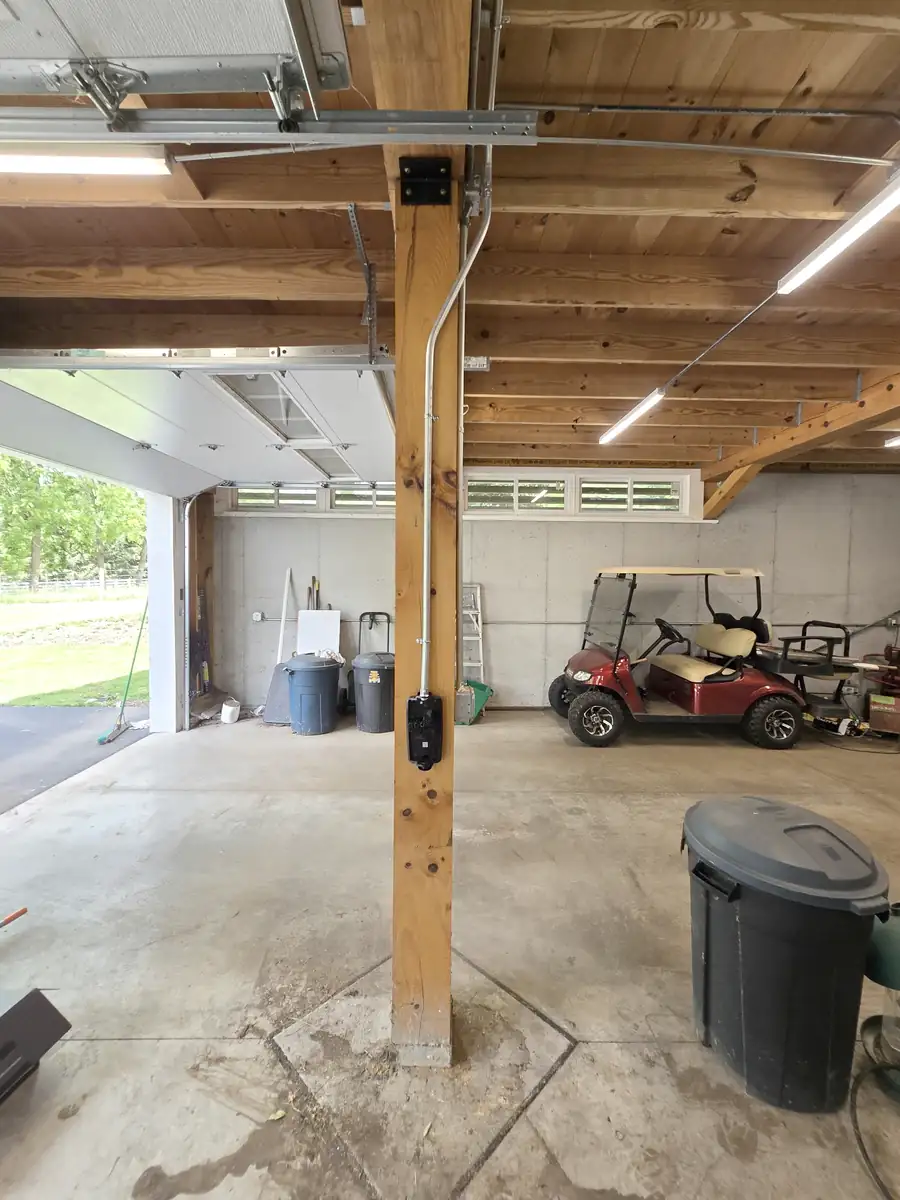 Surface EMT conduit run neatly along the exposed beam feeding the Tesla Wall Connector